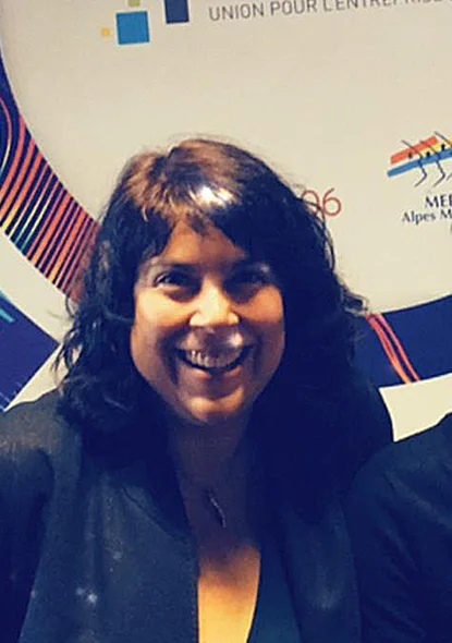 Elia avant sa reconversion, souriante en tenue professionnelle lors d’un événement corporate