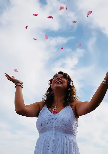 Elia, énergéticienne à Villeneuve Loubet, lance joyeusement des pétales de roses sous un ciel bleu
