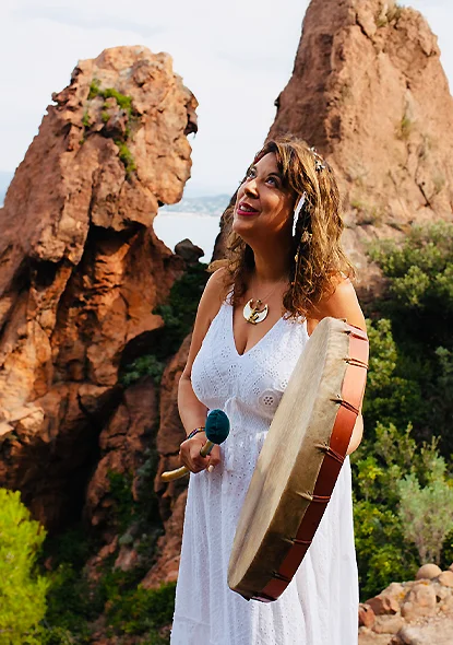 Elia jouant du tambour chamanique en pleine nature, pour illustrer son cheminement énergétique