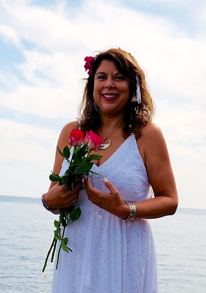 Elia, énergéticienne à Villeneuve Loubet, souriante en robe blanche, tenant un bouquet de roses contre son cœur