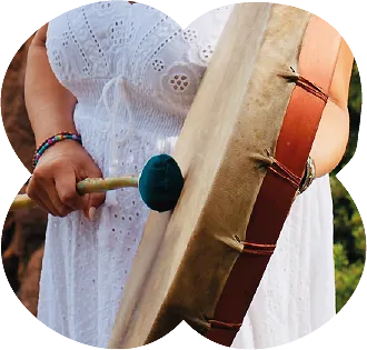 Main jouant du tambour chamanique lors d’un soin énergétique intuitif en pleine nature